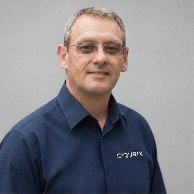 a man in a blue shirt with glasses and a grey background